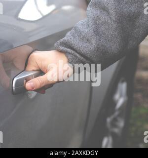 Die Hand des Mannes öffnet die Tür des silberfarbenen Wagens Stockfoto