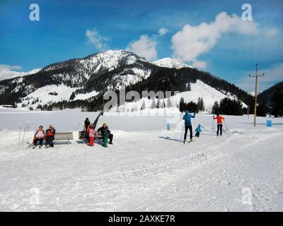 Hochfilzen, Österreich - 18. Februar 2012: Unbeschriftete Menschen entspannen sich in der Sonne und sportliche Menschen beim Skilangfahren Stockfoto