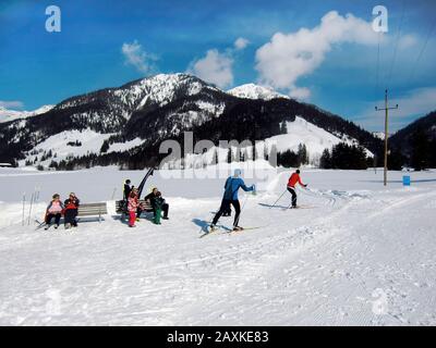 Hochfilzen, Österreich - 18. Februar 2012: Nicht identifizierte Menschen entspannen sich in der Sonne und sportliche Menschen beim Skilangläufer Stockfoto