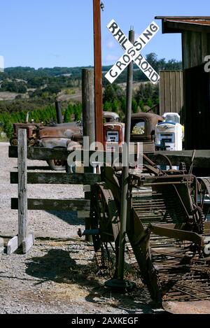 Eisenbahnübergangsschild und alte rostige Autos mit Gaspumpen auf einer Farm im Sonoma County, Kalifornien, USA Stockfoto