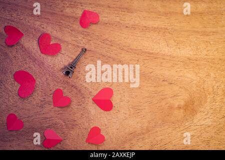 Miniatur-Eiffelturm mit roten kleinen Herzen auf strukturiertem Holzhintergrund mit Kopierraum. Konzept für die Liebe zum Paar, romantisches Poster, Cover, Sale PAM Stockfoto