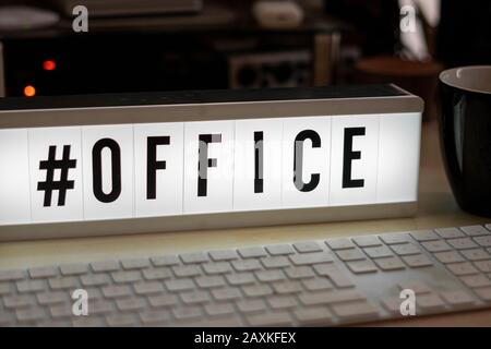 Auf einem weiß beleuchteten Kinosild steht mit schwarzen Buchstaben #Büro Stockfoto