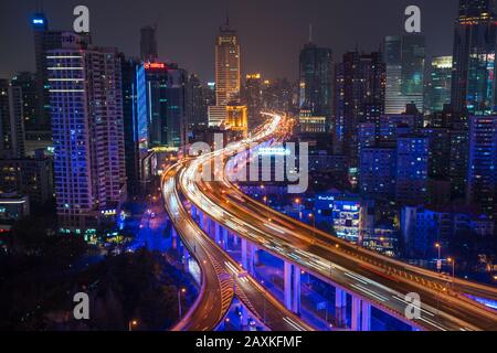 Erhöhter Blick auf gestapelte Straßenkreuzung und Skyline von Shanghai in der Abenddämmerung, Shanghai, China Stockfoto