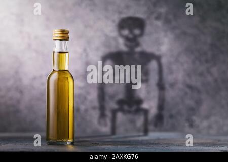 Eine Flasche Whisky mit einem Schatten in Form eines Skeletts. Konzept zum Schaden von Alkohol und schädlichen Gewohnheiten des Menschen Stockfoto