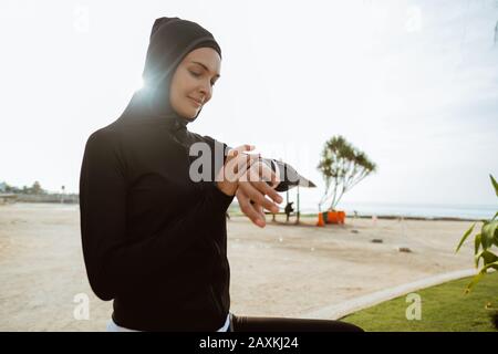 Sportbeobachterlauf muslimische Frau überprüft Smartwatch Tracker. Weibliche Läuferin mit Blick auf Herzfrequenzmesser SMART Watch Stockfoto