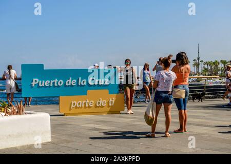 Touristen fotografieren gegen das Stadtschild von Puerto de la Cruz. santa Cruz Teneriffa, Kanarische Inseln. Stockfoto