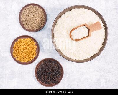 Würzen Sie schwarzen Pfeffer, Fenugreek, Kümmel (jeera) für Basmati-Reis mit langem Korn in der Schüssel, Schaufel, Tonplatte auf weißem Betongrund Stockfoto