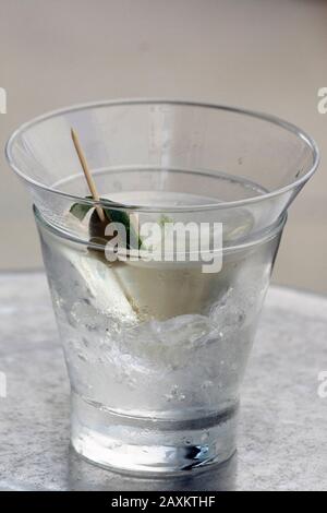 Glas alkoholisches Getränk mit Oliven-, Kalkschalen- und Eiswürfeln. Stockfoto