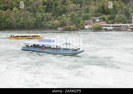 Rheinfall, Schweiz - 6. Mai 2017: Bootsfahrt zu den Rheinfällen, Touristen sind in Motorbooten auf unruhigen Gewässern Stockfoto