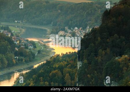 Blick auf das Dorf Wehlen im Tal im Nationalpark Sächsische Schweiz. Elbe mit Bäumen und Felsen in Herbststimmung. Stockfoto