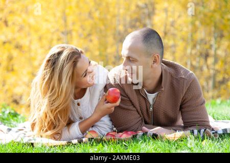 ????? Ein Paar hat Spaß beim liegen auf Gras beim Picknick am sonnigen Herbsttag im Park Stockfoto