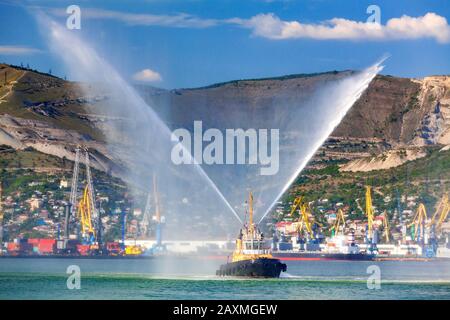 Schwimmendes Schleppboot sprüht Wasserstrahlen und demonstriert dabei Löschwasserkanonen Stockfoto