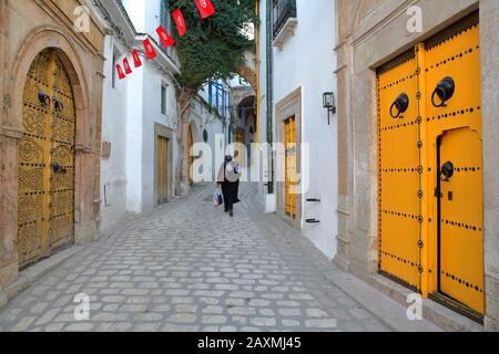 Typische gepflasterte und schmale Straße (dar el Jeld Straße) mit bunten Türen, Säulen und Arkaden in der historischen Medina von Tunis, Tunesien Stockfoto