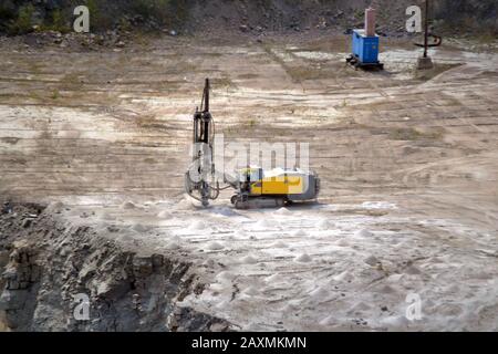 Gelbe Bohrmaschine in der Nähe eines Granit-Steinbruchs Stockfoto