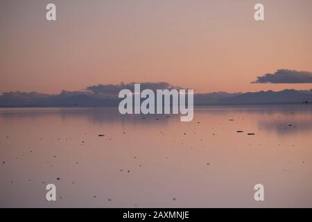 Sonnenuntergang über dem Wasser im Uyuni Salar reflektiert Stockfoto