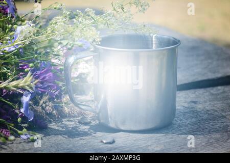 Metallbecher auf einem Tisch mit schönen Blumen, Filter, Stockfoto