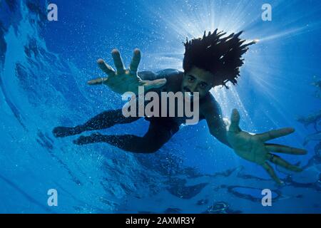 Ein afroamerikanischer männlicher Folkmusiker (Hunter Paye) mit Dreadlocks unter Wasser in einem Pool. (Modell freigegeben) Stockfoto
