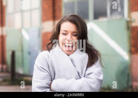 Junge Frau draußen stehend und lachend Stockfoto