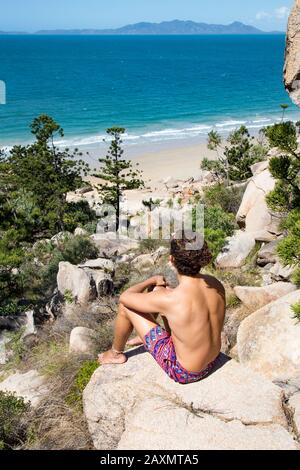 Junger Mann mit Haarbün und Badeanzug, Blick auf den Ozean Stockfoto