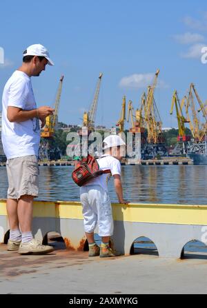 Mann und Kind auf dem Pier in der Nähe des Seehafens. Stadt Odessa, Ukraine 18. Juli 2013 Stockfoto