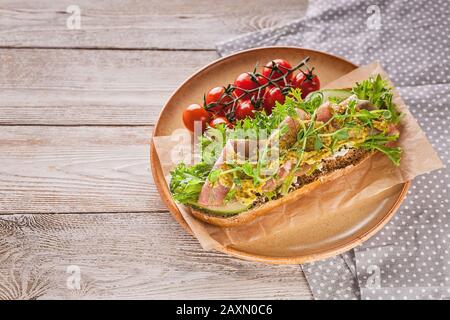 Bruschetta mit rohem Räucherfleisch, Frischkäse, Erbsen- und Pestosoße, Kirschtomaten auf einem Holztisch. Kopierbereich Stockfoto