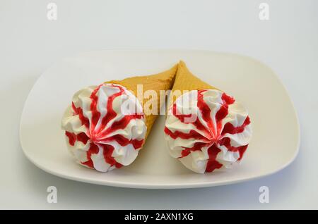 Zwei Erdbeer-Eiskegel auf weißem Teller, isoliert auf weißem Hintergrund, extreme Nahaufnahme Stockfoto