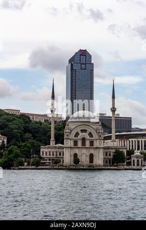 19. Juni 2019 - Istanbul, Türkei - Blick auf die Dolmabahçe-Moschee am Ufer der Bosporus-Straße, Süzer Plaza steht im Hintergrund Stockfoto