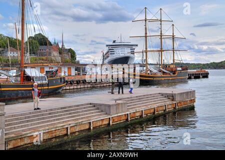 Historische Schiffe im Hafen im Oslo-Fjord mit der Festung Akershus und dem Transatlantikliner Queen Mary 2, Oslo, Norwegen Stockfoto