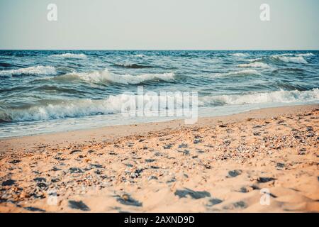 Das Meer und der sandige Strand, mit weißen Spitzen von Wellen, die am Ufer lappen, der Filter Stockfoto