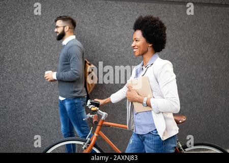 Fröhliche, fröhliche Geschäftsfrau, die mit dem Fahrrad arbeitet Stockfoto
