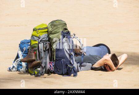 Zwei junge Leute mit großen Rucksäcken ruhen am Strand. Stockfoto