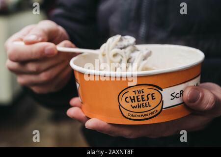 London, Großbritannien - 26. November 2019: Nahaufnahme eines Mannes, der Pasta vom Käseradstand im Camden Market, London, einer der meistfrequentierten Desti im Einzelhandel, isst Stockfoto