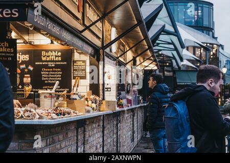 London, Großbritannien - 26. November 2019: Reihe von Lebensmittelständen auf dem Camden Market, London, Menschen gehen vorbei, selektiver Fokus. Begonnen wurde mit 16 Ständen 1974, Camden M Stockfoto