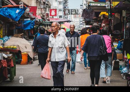 Hongkong, China - November 2019: Alter asiatischer Mann kauft Lebensmittel auf dem Straßennahrungsmittelmarkt in Hongkong Stockfoto