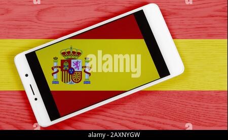 Flagge Spaniens, die sich durch das Aufstellen eines Smartphones mit seinem Symbol auf einem farbigen Holzhintergrund zusammensetzt Stockfoto