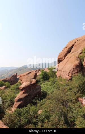 Große rote Felsen Sandstein Felsformationen mit Bäumen und Büschen wächst in den Spalten der Felsen mit Bäumen gesäumten Berge im Hintergrund auf der Tradi Stockfoto