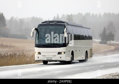 Weißer Reisebus, der im Winter auf der Landstraße unterwegs ist. Stockfoto