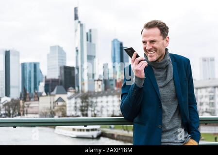 Geschäftsmann mit Smartphone vor der Skyline am Main, Frankfurt am Main, Hessen, Deutschland Stockfoto