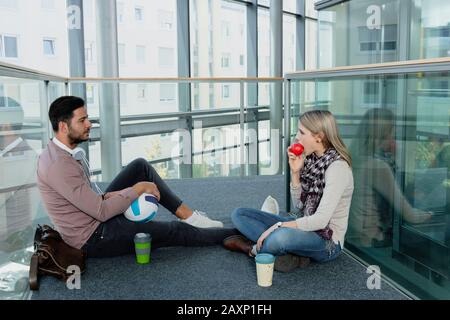 Junge Frau und junger Mann im modernen Bürogebäude machen Pause Stockfoto