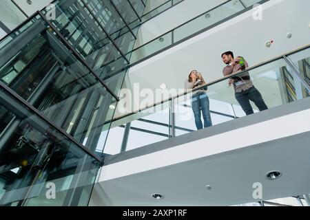 Junge Frau und junger Mann im modernen Bürogebäude machen Pause Stockfoto