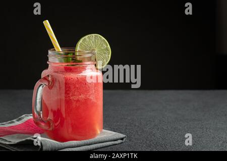 Wassermelone Smoothie mit Limette und Minze im Becher Glas auf einem Schneidebrett. Gesunde Ernährung Konzept, Copyspace Stockfoto