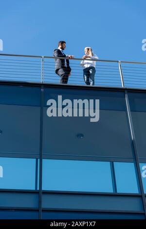 Junger Geschäftsmann und junge Geschäftsfrau auf der Dachterrasse des modernen Bürogebäudes Stockfoto