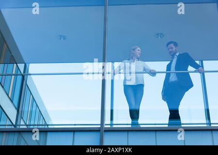 Junger Geschäftsmann und junge Geschäftsfrau im modernen Bürogebäude hinter Glasfront Stockfoto