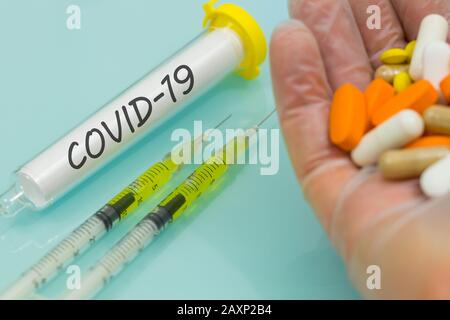 COVID-19 in einer Durchstechflasche Hand in Gummihandschuh mit Medikamenten und Injektionen. Konzept der Arbeit an einem Virusimpfstoff Stockfoto