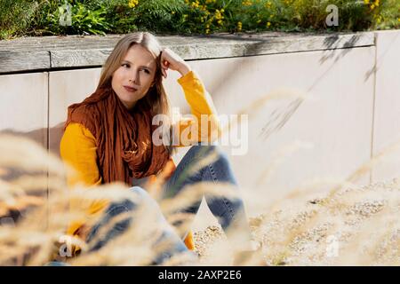 Junge Frau sitzt im Park auf dem Boden Stockfoto