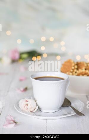 Kaffeetasse mit Rose und Keksen vor hellem Hintergrund Stockfoto