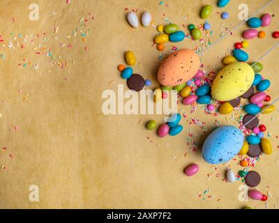 Bunte Ostereier, Süßigkeiten auf gelbem Hintergrund, Kopierraum Stockfoto