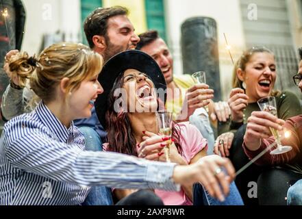 Laute fröhliche Freunde feiern Party mit Champagner, Konfetti und Sparklern im Freien - Jugendliche feiern Geburtstag trinken und lachen - fest Konzept Stockfoto