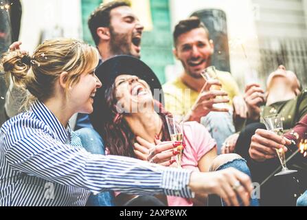 Fröhliche Freunde, die mit einem Feuerwerk feiern, das Champagner im Freien trinkt - Junge Millennials, die draußen Party machen - Jugend, Freundschaft und t Stockfoto