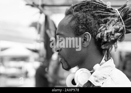 Portrait des nachdenklichen schwarzen Mannes im Freien auf einem wöchentlichen Wäschemarkt - Junger Rasta Kerl mit Kopfhörern in New York - Love Sadness Concept - Black and Stockfoto
